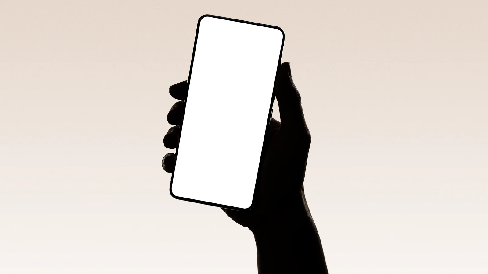 A hand holds a smartphone with a blank white screen against a soft neutral background.